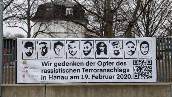 Auf dem Bild ist ein vor dem Bertha-Pappenheim-Haus in Neu-Isenburg angebrachter Banner zu sehen, der die Gesichter der neun bei dem Anschlag ermordeten Personen zeigt.