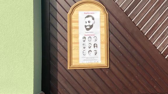 Die Gedenkplakate zum Anschlag in Hanau hängen an einem Holztor 